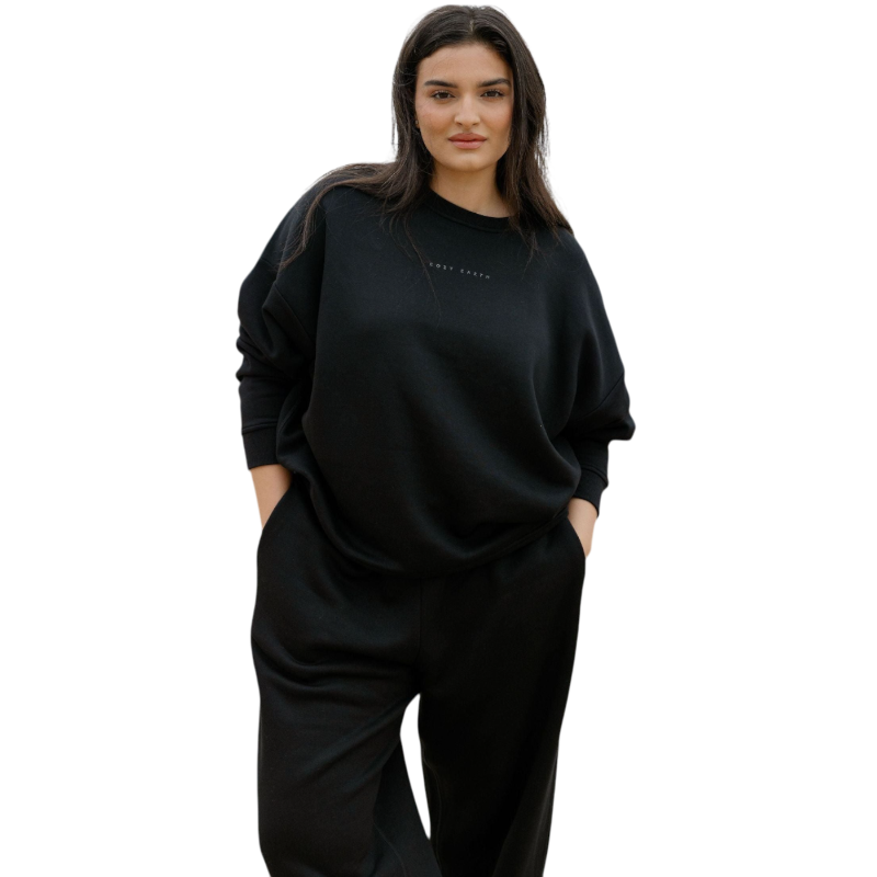 A person with curly hair models the Cozy Earth Women's CityScape Crewneck and matching pants in light pink against a plain white backdrop. |Color:Peony