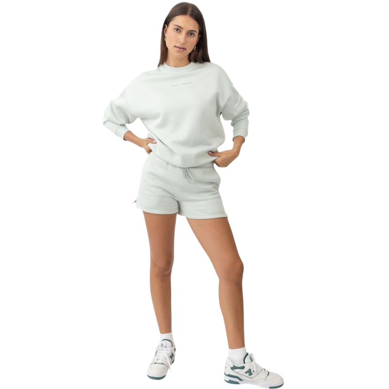 A person with curly hair models the Cozy Earth Women's CityScape Crewneck and matching pants in light pink against a plain white backdrop. |Color:Peony