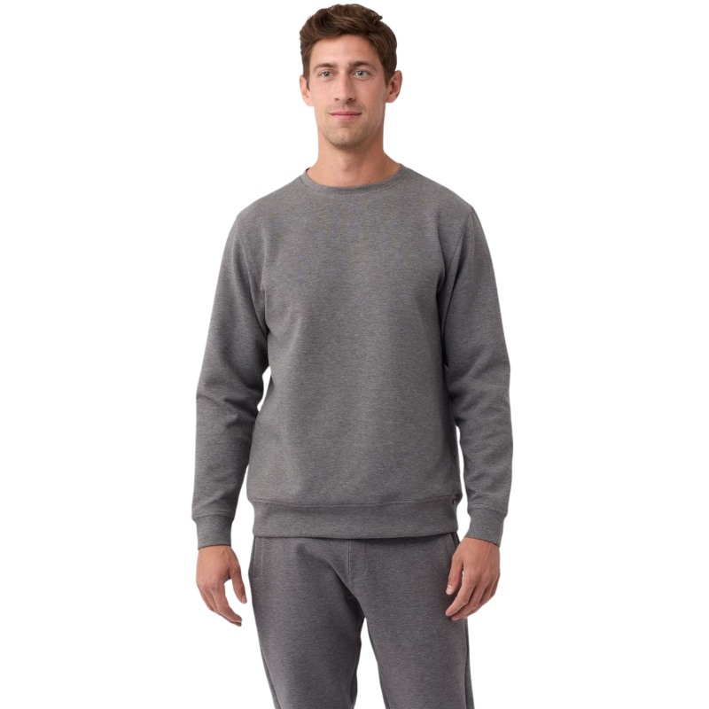 A man is wearing the Men's StretchTech Crewneck sweatshirt from Cozy Earth, paired with matching sweatpants. He stands against a plain white background with short brown hair, looking forward with a neutral expression. |Color:Coal Heather