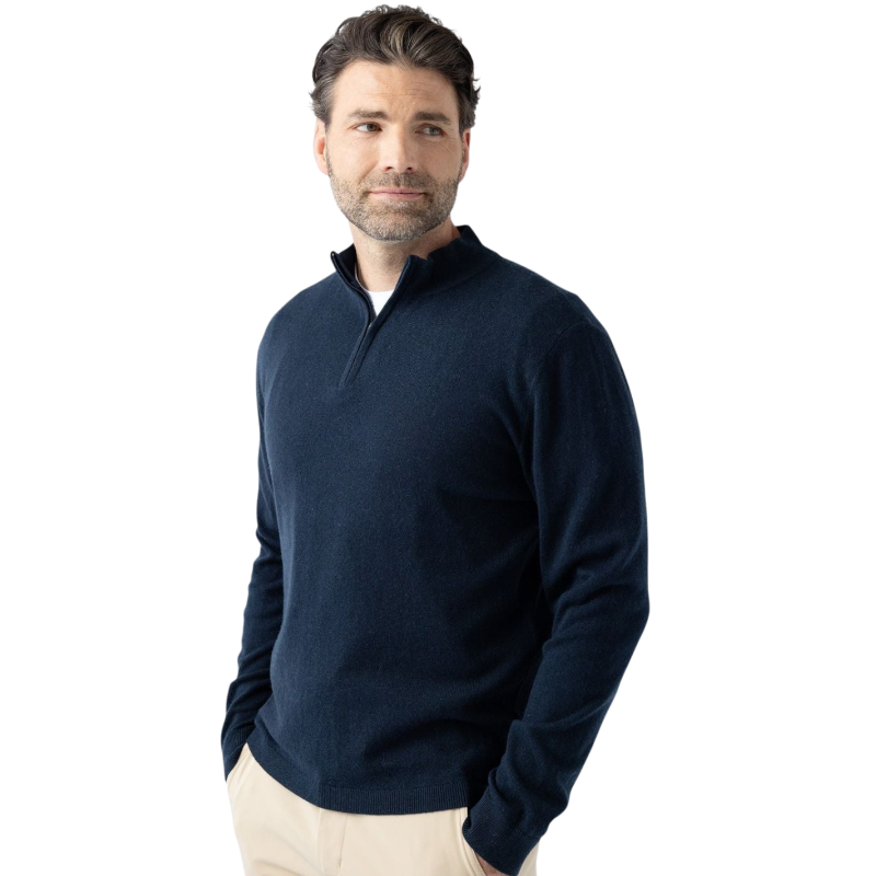 A man with dark hair and a short beard is wearing a navy blue Men's Quarter Zip Sweater from Cozy Earth paired with beige pants. He stands with his hands in his pockets against a plain white background, looking to his right with a slight smile. |Color:Eclipse