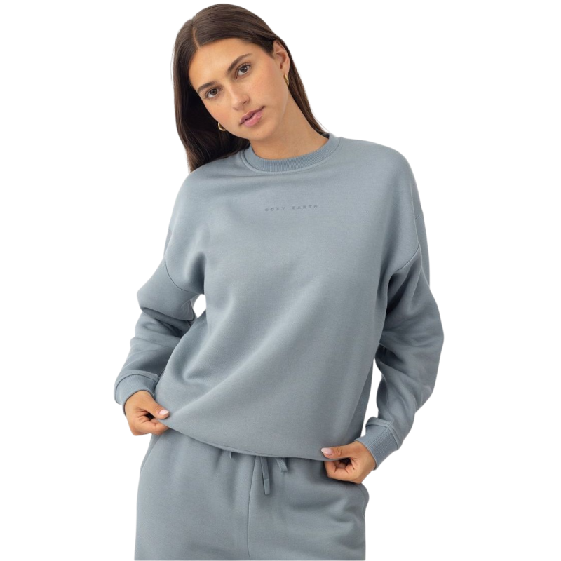 A person with curly hair models the Cozy Earth Women's CityScape Crewneck and matching pants in light pink against a plain white backdrop. |Color:Peony