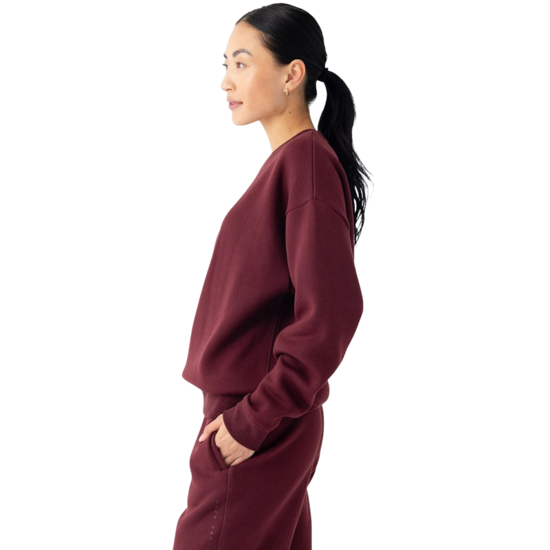 A person with curly hair models the Cozy Earth Women's CityScape Crewneck and matching pants in light pink against a plain white backdrop. |Color:Peony