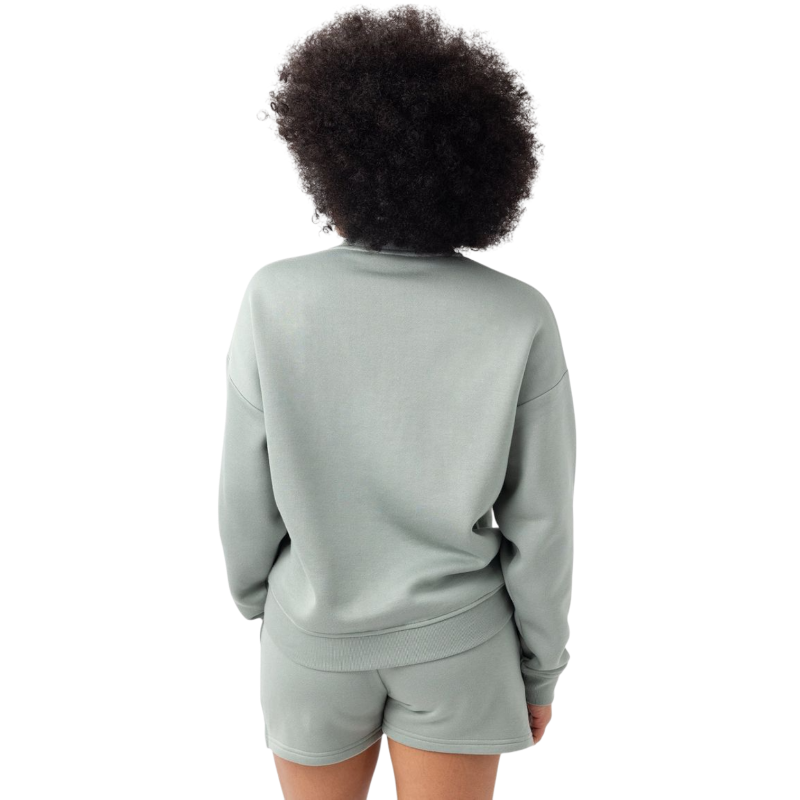 A person with curly hair models the Cozy Earth Women's CityScape Crewneck and matching pants in light pink against a plain white backdrop. |Color:Peony