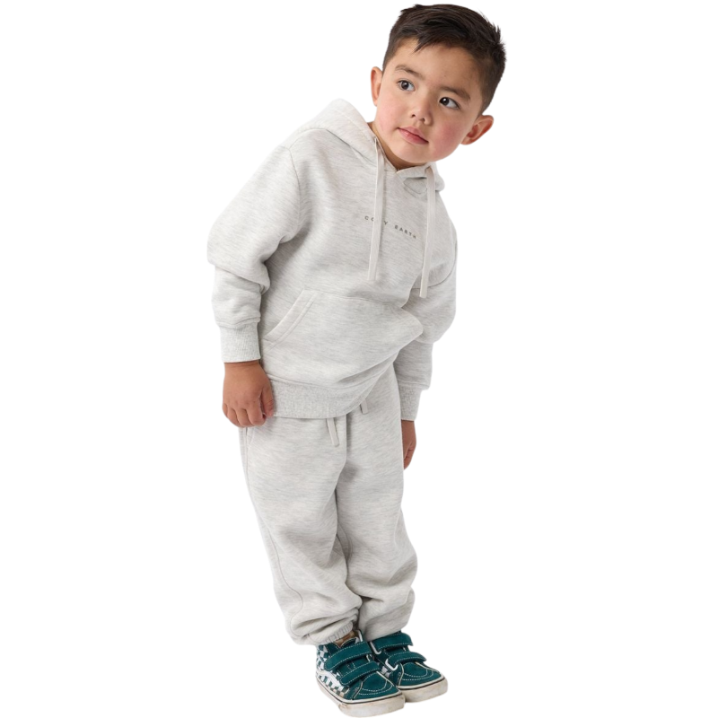 A young child with long blonde hair smiles while wearing a navy blue Kid's CityScape Hoodie by Cozy Earth and matching pants. She has two hair ties, one pink and one blue. The background is plain white. |Color:Eclipse