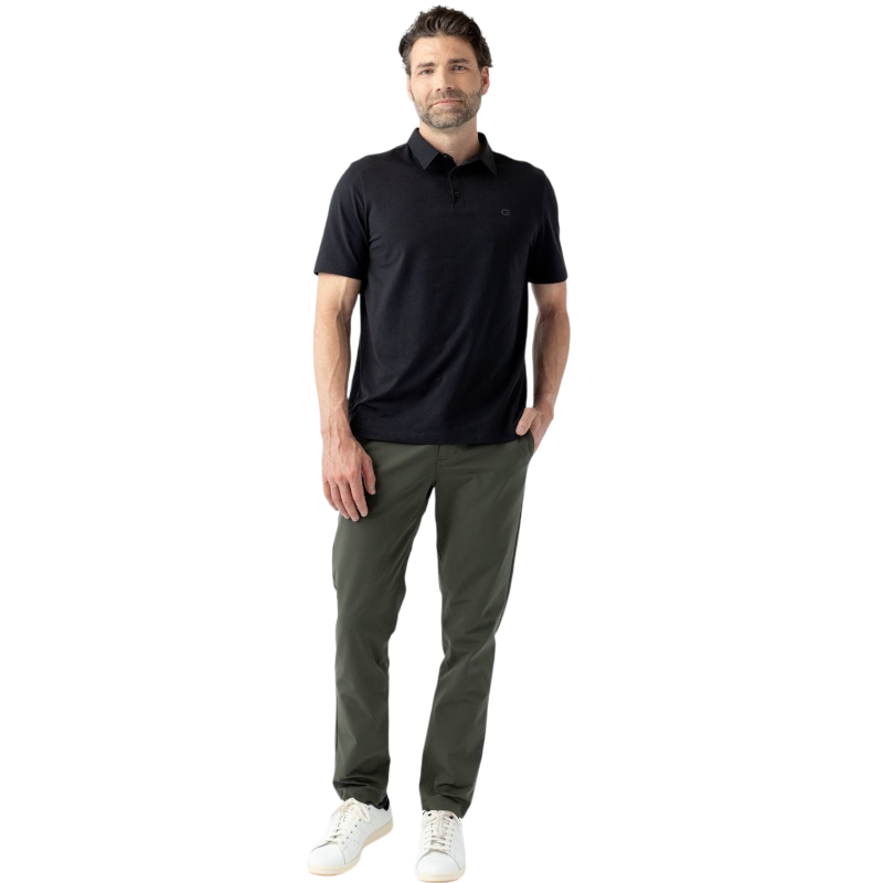 A person with short, light brown hair is wearing the Men's Everyday Polo by Cozy Earth in a light gray shade, paired with light beige pants. They are standing and slightly looking over their left shoulder with a neutral expression against a plain white background. |Color:Stone