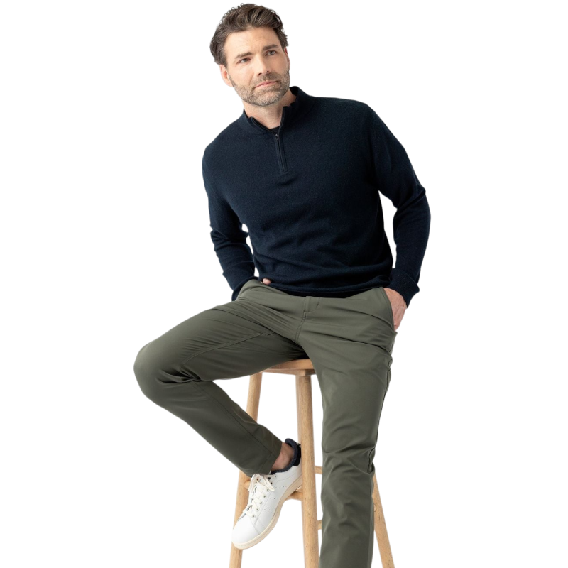 A man with dark hair and a short beard is wearing a navy blue Men's Quarter Zip Sweater from Cozy Earth paired with beige pants. He stands with his hands in his pockets against a plain white background, looking to his right with a slight smile. |Color:Eclipse