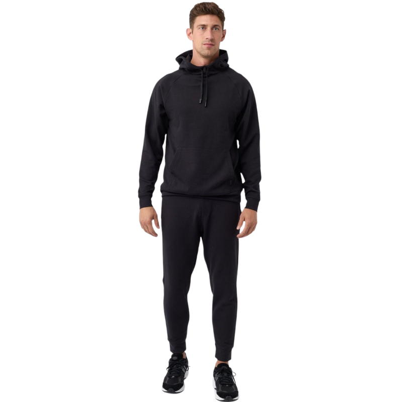 A person wearing the Men's StretchTech Hoodie from Cozy Earth, paired with matching gray pants, stands against a plain white background. The hoodie features drawstrings and a front pocket. The individual is looking forward with a neutral expression. |Color:Coal Heather