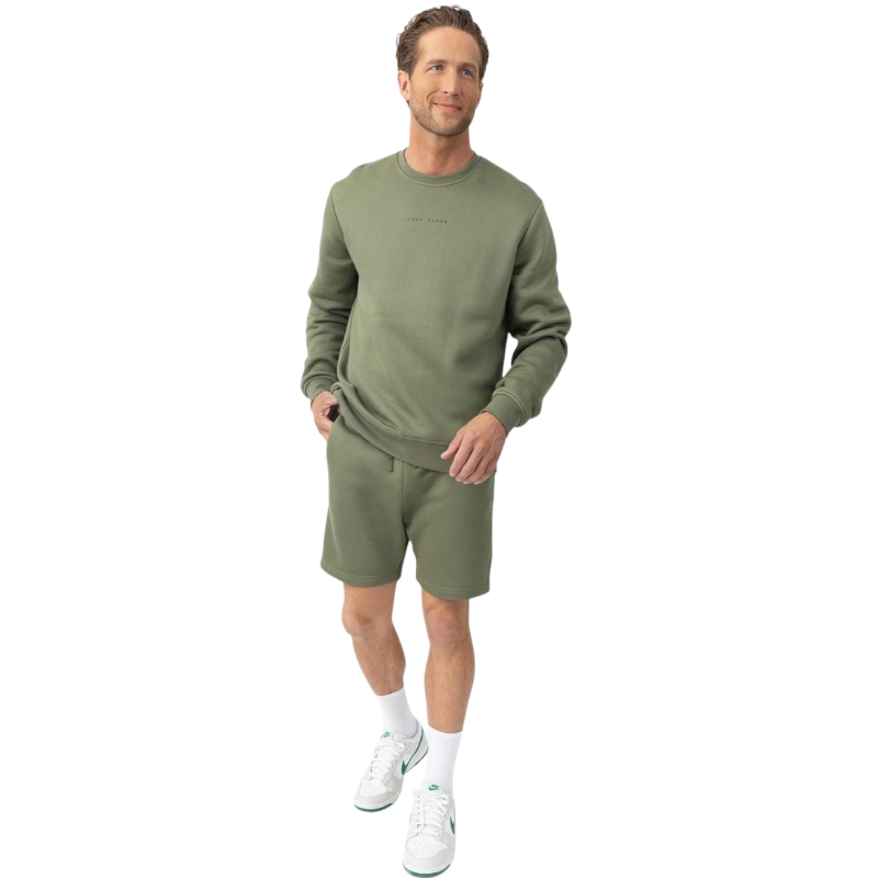 A man with short brown hair is wearing a dark green Men's CityScape Crewneck from Cozy Earth, featuring the words "COLD EARTH" printed on it. He is gazing slightly to the side against a plain white background. |Color:Spruce