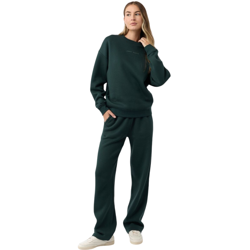 A person with curly hair models the Cozy Earth Women's CityScape Crewneck and matching pants in light pink against a plain white backdrop. |Color:Peony