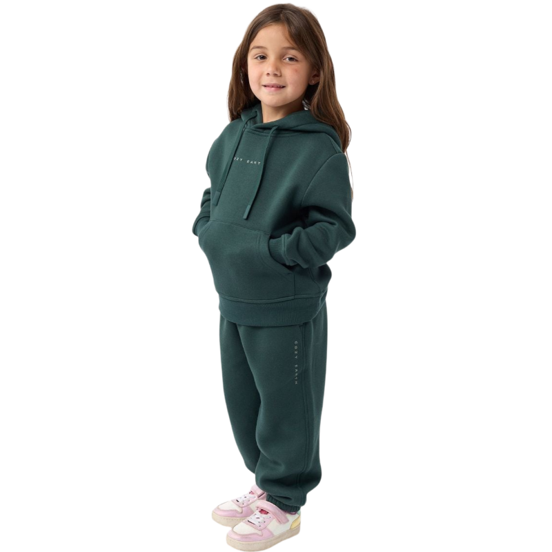 A young child with long blonde hair smiles while wearing a navy blue Kid's CityScape Hoodie by Cozy Earth and matching pants. She has two hair ties, one pink and one blue. The background is plain white. |Color:Eclipse