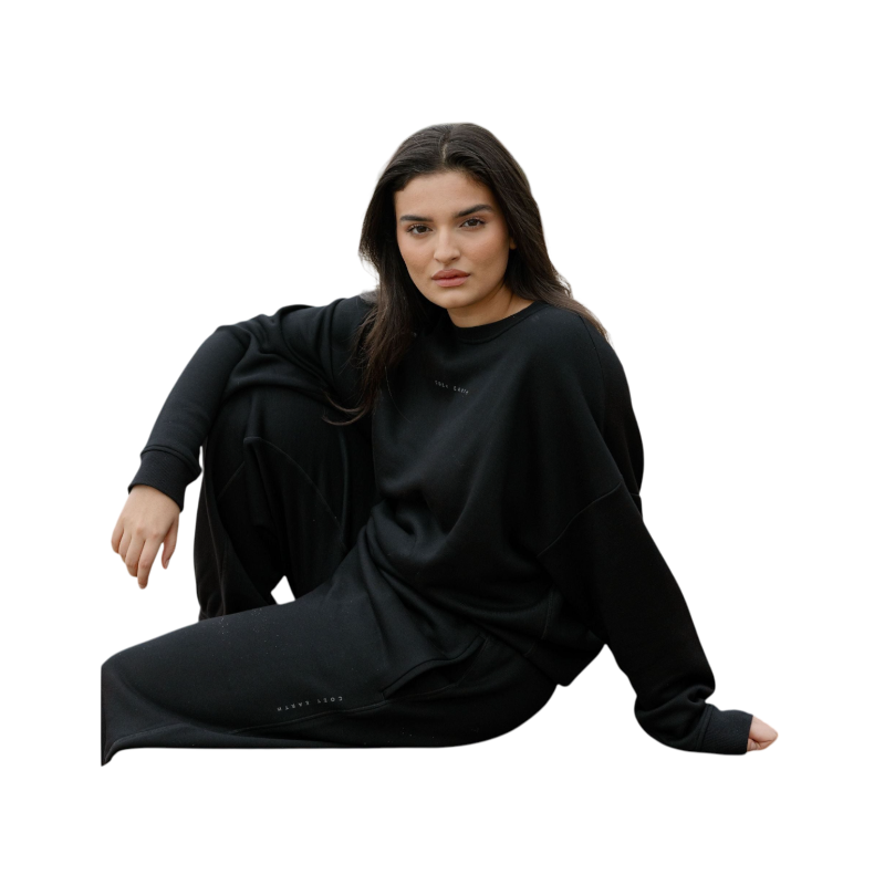 A person with curly hair models the Cozy Earth Women's CityScape Crewneck and matching pants in light pink against a plain white backdrop. |Color:Peony