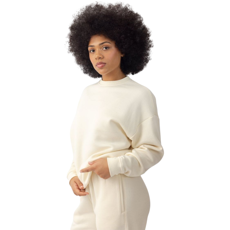 A person with curly hair models the Cozy Earth Women's CityScape Crewneck and matching pants in light pink against a plain white backdrop. |Color:Peony