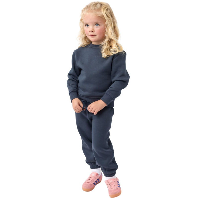 A young boy with blond hair is wearing the Cozy Earth Kid's CityScape Crewneck sweatshirt along with matching pants. He is standing, smiling, and looking slightly to the side against a plain white background. |Color:Eclipse