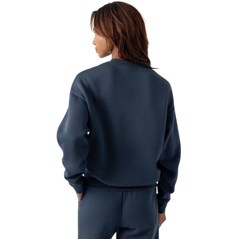 A person with curly hair models the Cozy Earth Women's CityScape Crewneck and matching pants in light pink against a plain white backdrop. |Color:Peony