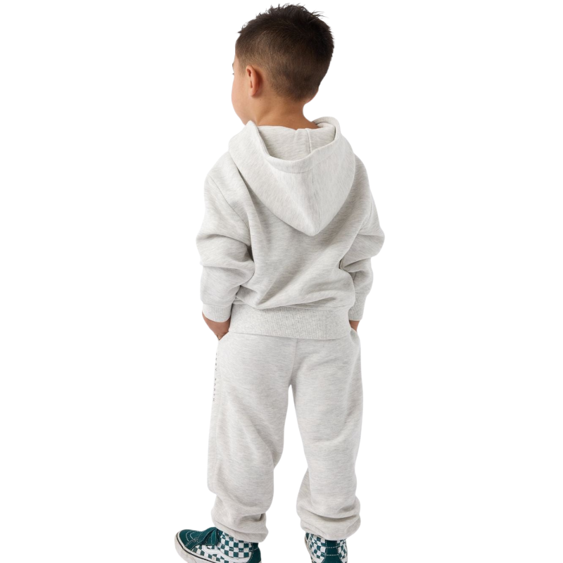 A young child with long blonde hair smiles while wearing a navy blue Kid's CityScape Hoodie by Cozy Earth and matching pants. She has two hair ties, one pink and one blue. The background is plain white. |Color:Eclipse