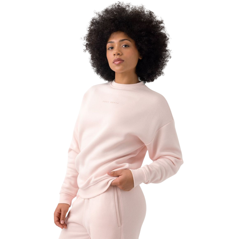 A person with curly hair models the Cozy Earth Women's CityScape Crewneck and matching pants in light pink against a plain white backdrop. |Color:Peony