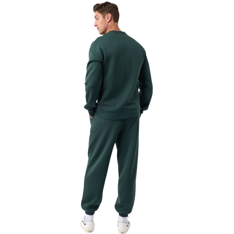 A man with short brown hair is wearing a dark green Men's CityScape Crewneck from Cozy Earth, featuring the words "COLD EARTH" printed on it. He is gazing slightly to the side against a plain white background. |Color:Spruce