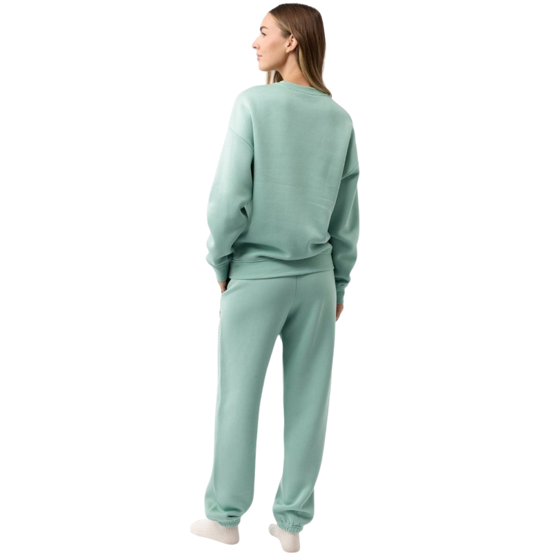 A person with curly hair models the Cozy Earth Women's CityScape Crewneck and matching pants in light pink against a plain white backdrop. |Color:Peony