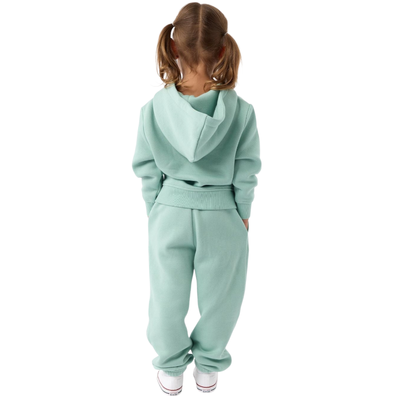 A young child with long blonde hair smiles while wearing a navy blue Kid's CityScape Hoodie by Cozy Earth and matching pants. She has two hair ties, one pink and one blue. The background is plain white. |Color:Eclipse