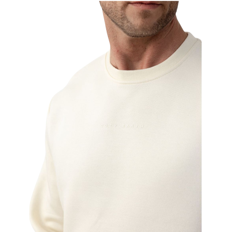 A man with short brown hair is wearing a dark green Men's CityScape Crewneck from Cozy Earth, featuring the words "COLD EARTH" printed on it. He is gazing slightly to the side against a plain white background. |Color:Spruce