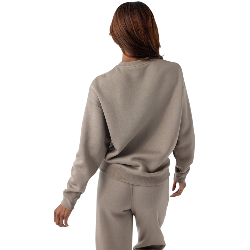 A person with curly hair models the Cozy Earth Women's CityScape Crewneck and matching pants in light pink against a plain white backdrop. |Color:Peony