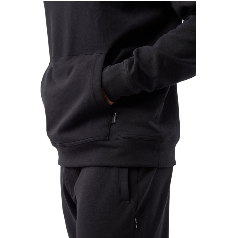A person wearing the Men's StretchTech Hoodie from Cozy Earth, paired with matching gray pants, stands against a plain white background. The hoodie features drawstrings and a front pocket. The individual is looking forward with a neutral expression. |Color:Coal Heather