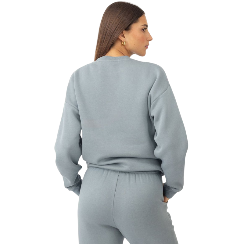 A person with curly hair models the Cozy Earth Women's CityScape Crewneck and matching pants in light pink against a plain white backdrop. |Color:Peony