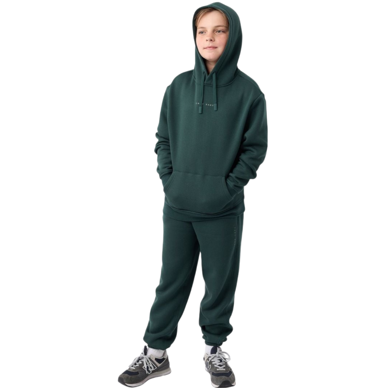 A young child with long blonde hair smiles while wearing a navy blue Kid's CityScape Hoodie by Cozy Earth and matching pants. She has two hair ties, one pink and one blue. The background is plain white. |Color:Eclipse