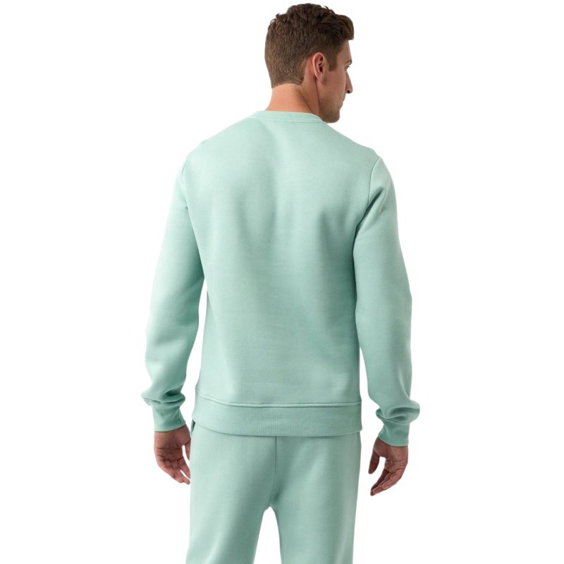 A man with short brown hair is wearing a dark green Men's CityScape Crewneck from Cozy Earth, featuring the words "COLD EARTH" printed on it. He is gazing slightly to the side against a plain white background. |Color:Spruce