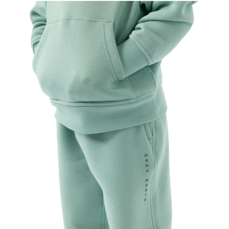 A young child with long blonde hair smiles while wearing a navy blue Kid's CityScape Hoodie by Cozy Earth and matching pants. She has two hair ties, one pink and one blue. The background is plain white. |Color:Eclipse