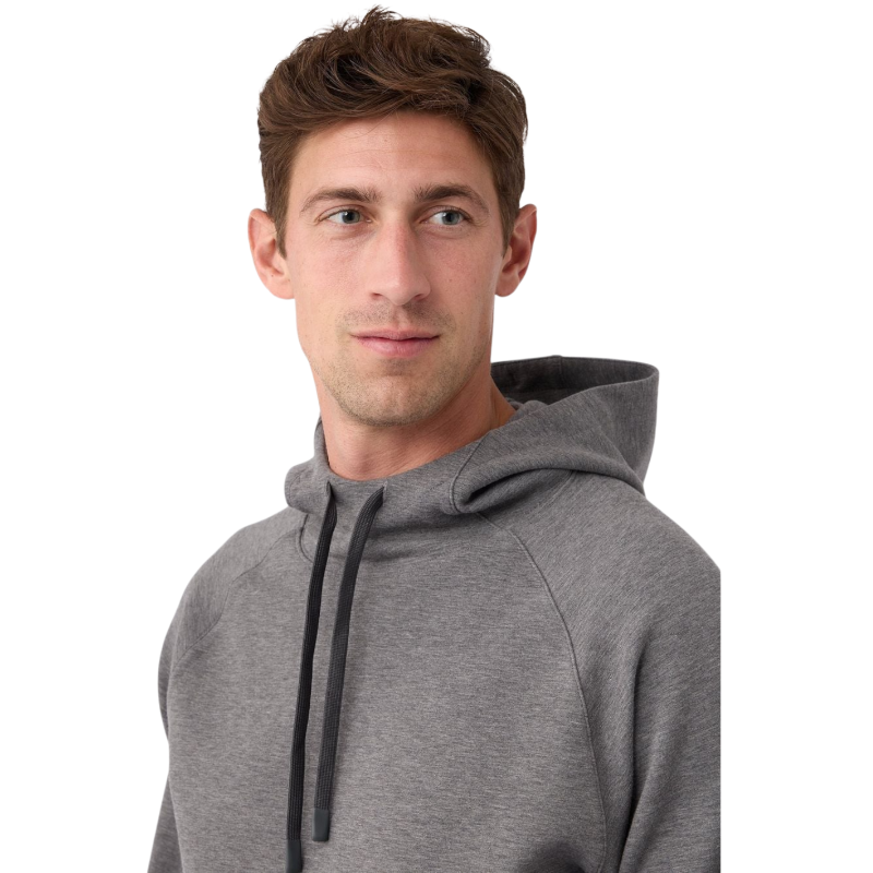 A person wearing the Men's StretchTech Hoodie from Cozy Earth, paired with matching gray pants, stands against a plain white background. The hoodie features drawstrings and a front pocket. The individual is looking forward with a neutral expression. |Color:Coal Heather