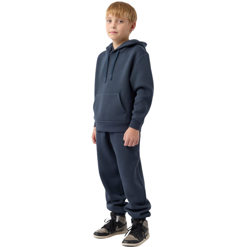 A young child with long blonde hair smiles while wearing a navy blue Kid's CityScape Hoodie by Cozy Earth and matching pants. She has two hair ties, one pink and one blue. The background is plain white. |Color:Eclipse