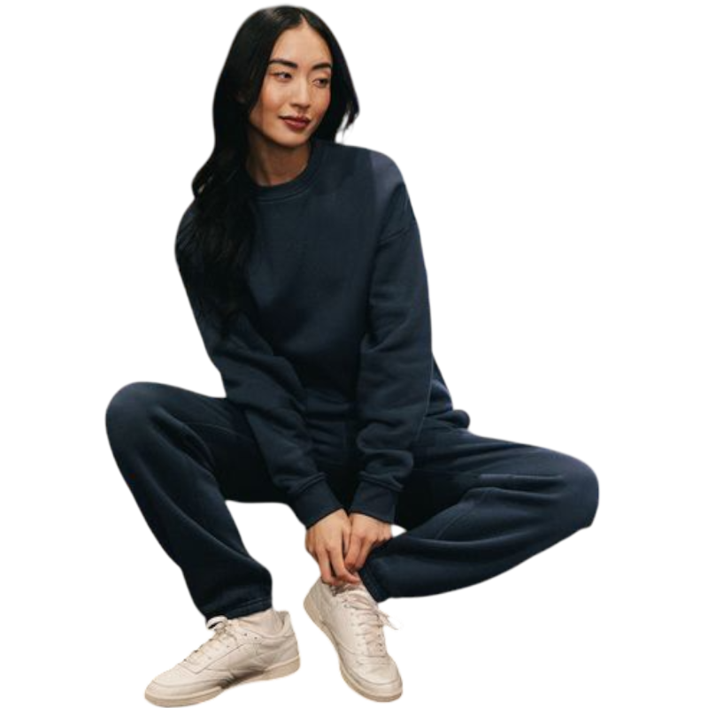 A person with curly hair models the Cozy Earth Women's CityScape Crewneck and matching pants in light pink against a plain white backdrop. |Color:Peony