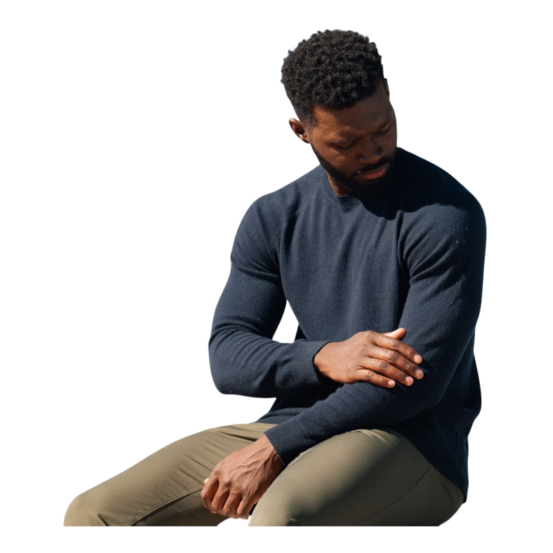 A man with dark hair and a beard stands casually with his hands in his pockets. He is wearing the Cozy Earth Men's Crewneck Sweater in navy blue, paired with gray pants. He looks at the camera with a neutral expression, set against a plain white background. |Color:Eclipse