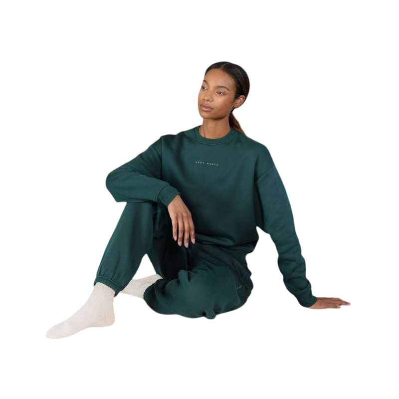A person with curly hair models the Cozy Earth Women's CityScape Crewneck and matching pants in light pink against a plain white backdrop. |Color:Peony