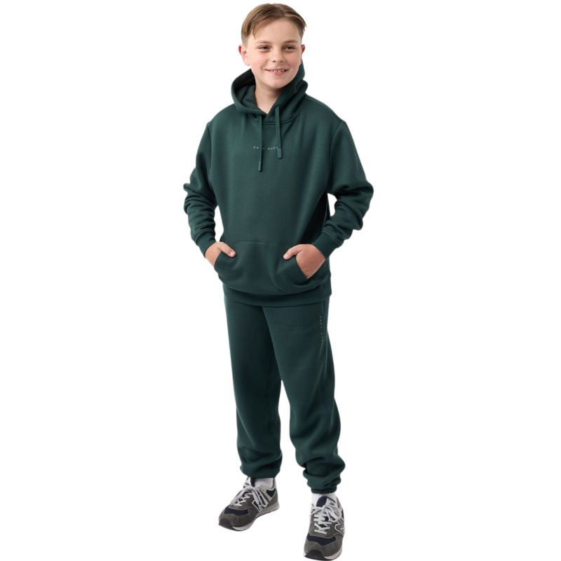 A young child with long blonde hair smiles while wearing a navy blue Kid's CityScape Hoodie by Cozy Earth and matching pants. She has two hair ties, one pink and one blue. The background is plain white. |Color:Eclipse