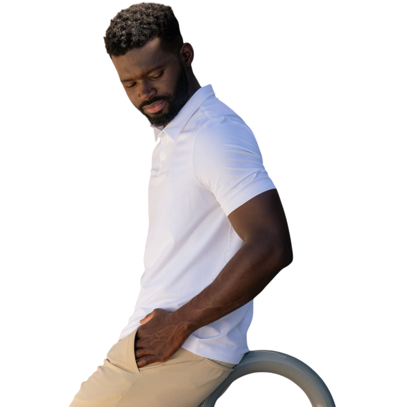 A person with short, light brown hair is wearing the Men's Everyday Polo by Cozy Earth in a light gray shade, paired with light beige pants. They are standing and slightly looking over their left shoulder with a neutral expression against a plain white background. |Color:Stone