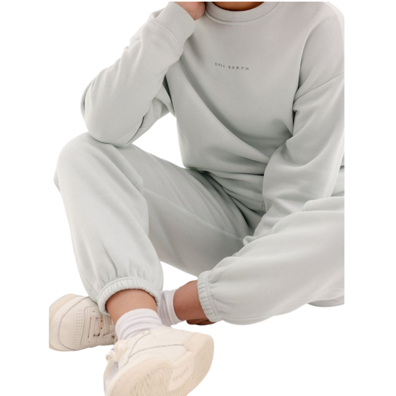 A person with curly hair models the Cozy Earth Women's CityScape Crewneck and matching pants in light pink against a plain white backdrop. |Color:Peony
