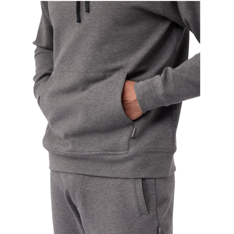 A person wearing the Men's StretchTech Hoodie from Cozy Earth, paired with matching gray pants, stands against a plain white background. The hoodie features drawstrings and a front pocket. The individual is looking forward with a neutral expression. |Color:Coal Heather