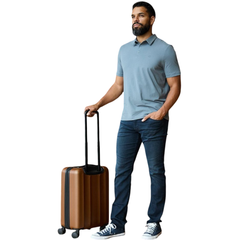 A person with short, light brown hair is wearing the Men's Everyday Polo by Cozy Earth in a light gray shade, paired with light beige pants. They are standing and slightly looking over their left shoulder with a neutral expression against a plain white background. |Color:Stone