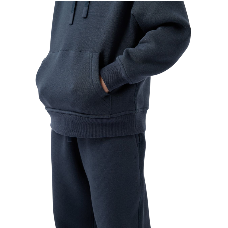 A young child with long blonde hair smiles while wearing a navy blue Kid's CityScape Hoodie by Cozy Earth and matching pants. She has two hair ties, one pink and one blue. The background is plain white. |Color:Eclipse