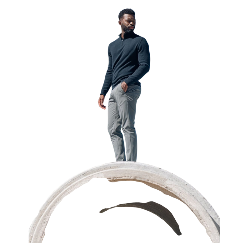 A man with dark hair and a short beard is wearing a navy blue Men's Quarter Zip Sweater from Cozy Earth paired with beige pants. He stands with his hands in his pockets against a plain white background, looking to his right with a slight smile. |Color:Eclipse