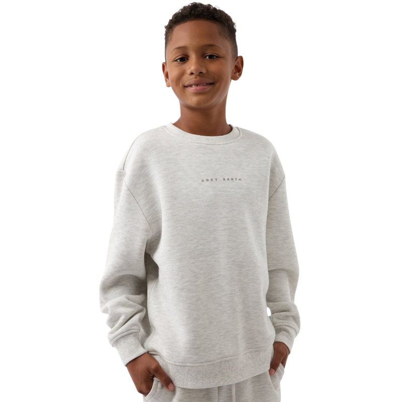 A young boy with blond hair is wearing the Cozy Earth Kid's CityScape Crewneck sweatshirt along with matching pants. He is standing, smiling, and looking slightly to the side against a plain white background. |Color:Eclipse