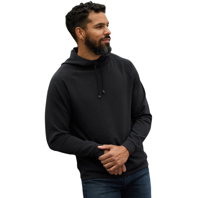 A person wearing the Men's StretchTech Hoodie from Cozy Earth, paired with matching gray pants, stands against a plain white background. The hoodie features drawstrings and a front pocket. The individual is looking forward with a neutral expression. |Color:Coal Heather