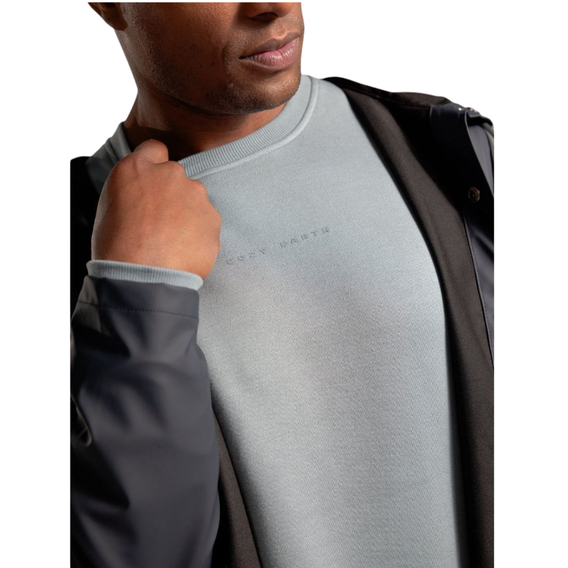 A man with short brown hair is wearing a dark green Men's CityScape Crewneck from Cozy Earth, featuring the words "COLD EARTH" printed on it. He is gazing slightly to the side against a plain white background. |Color:Spruce