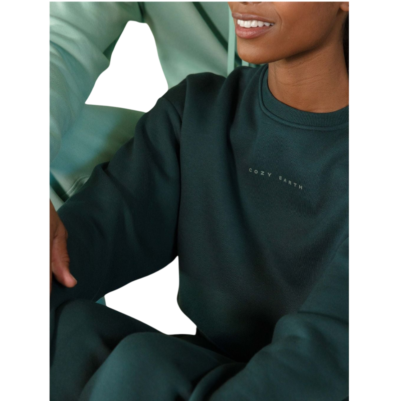 A person with curly hair models the Cozy Earth Women's CityScape Crewneck and matching pants in light pink against a plain white backdrop. |Color:Peony