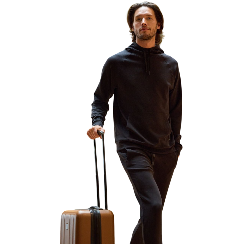 A person wearing the Men's StretchTech Hoodie from Cozy Earth, paired with matching gray pants, stands against a plain white background. The hoodie features drawstrings and a front pocket. The individual is looking forward with a neutral expression. |Color:Coal Heather