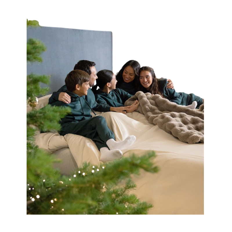 A young child with long blonde hair smiles while wearing a navy blue Kid's CityScape Hoodie by Cozy Earth and matching pants. She has two hair ties, one pink and one blue. The background is plain white. |Color:Eclipse