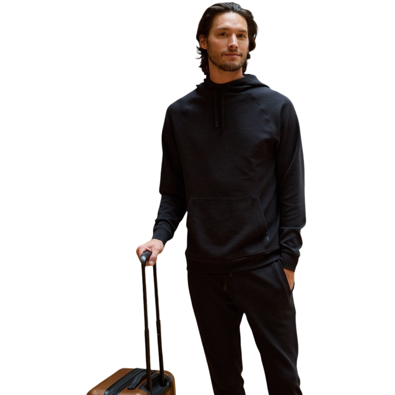 A person wearing the Men's StretchTech Hoodie from Cozy Earth, paired with matching gray pants, stands against a plain white background. The hoodie features drawstrings and a front pocket. The individual is looking forward with a neutral expression. |Color:Coal Heather