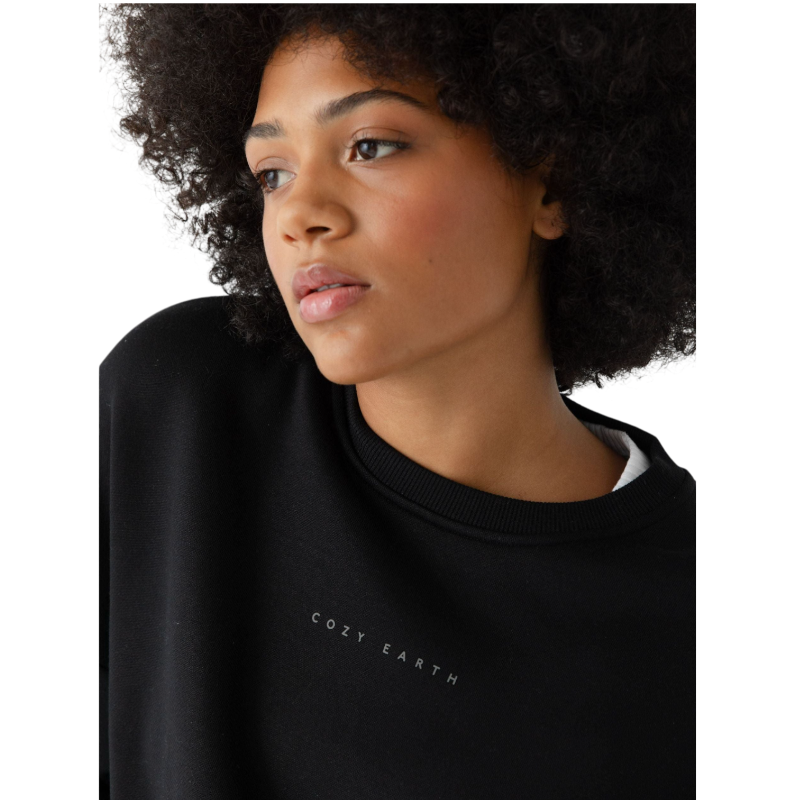 A person with curly hair models the Cozy Earth Women's CityScape Crewneck and matching pants in light pink against a plain white backdrop. |Color:Peony